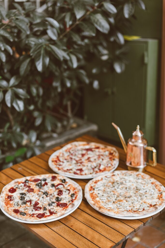 Pizzas with different toppings on an outside table.