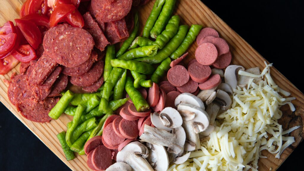 Different types of pizza toppings are displayed on a cutting board.