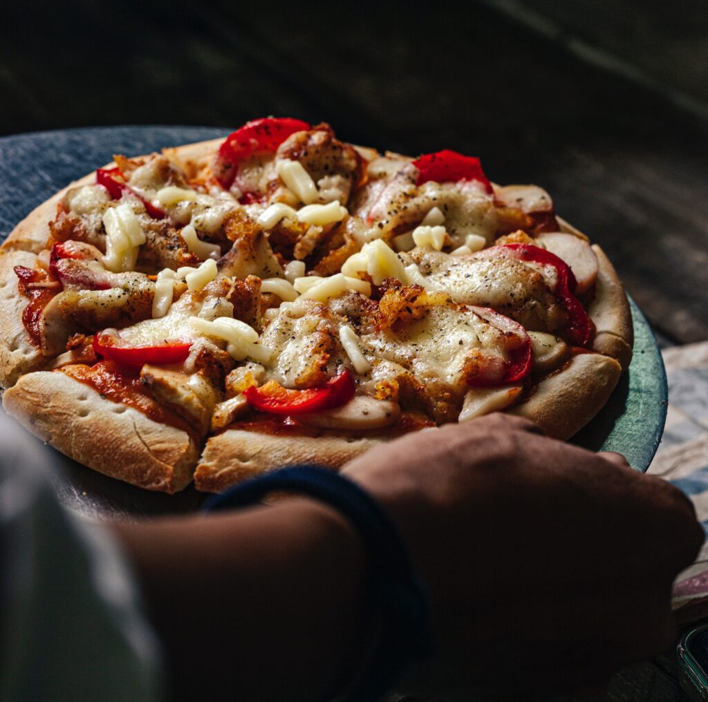 A person holding a tasty homemade pizza.