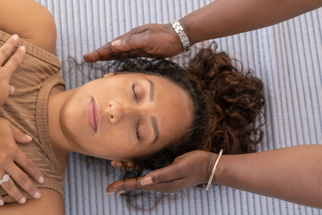 An African-American woman receiving Reiki treatment.