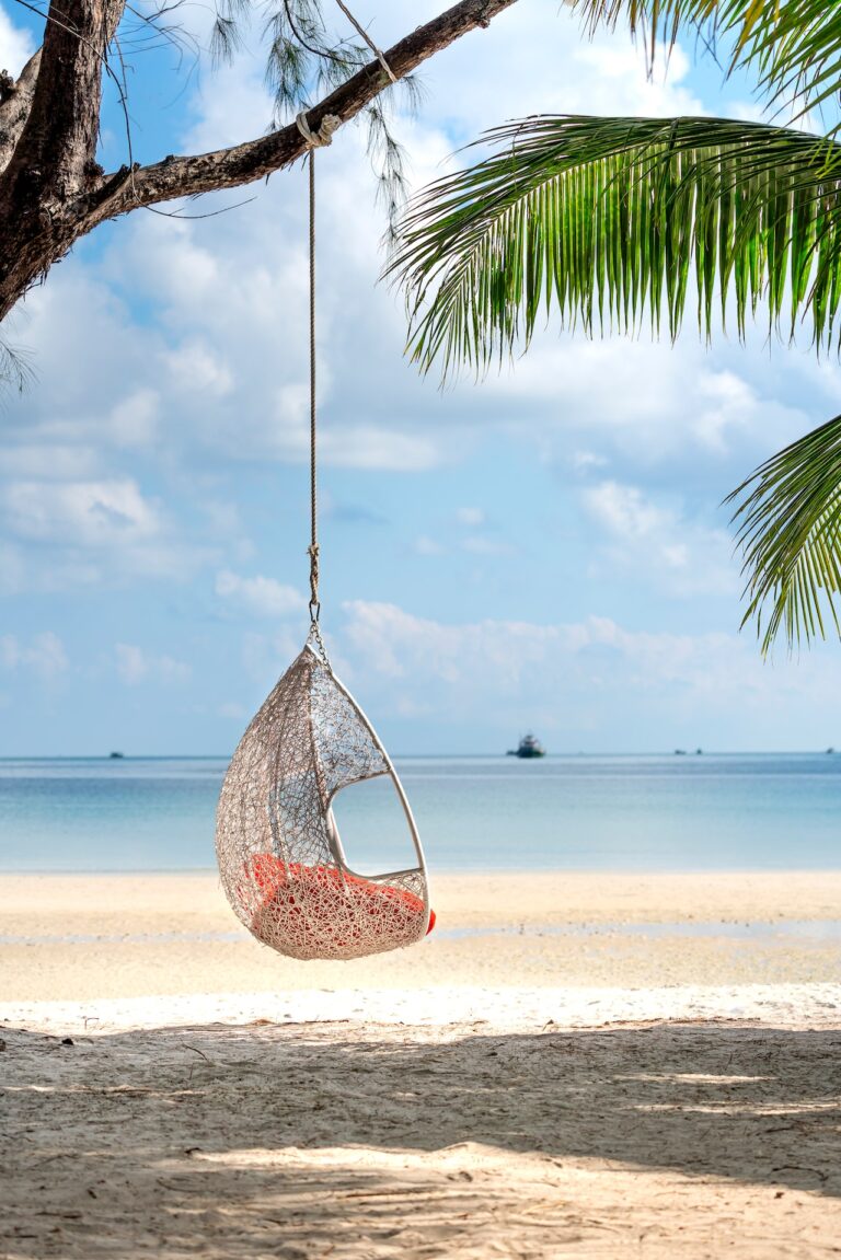 A hanging basket chair on a beautiful beach.